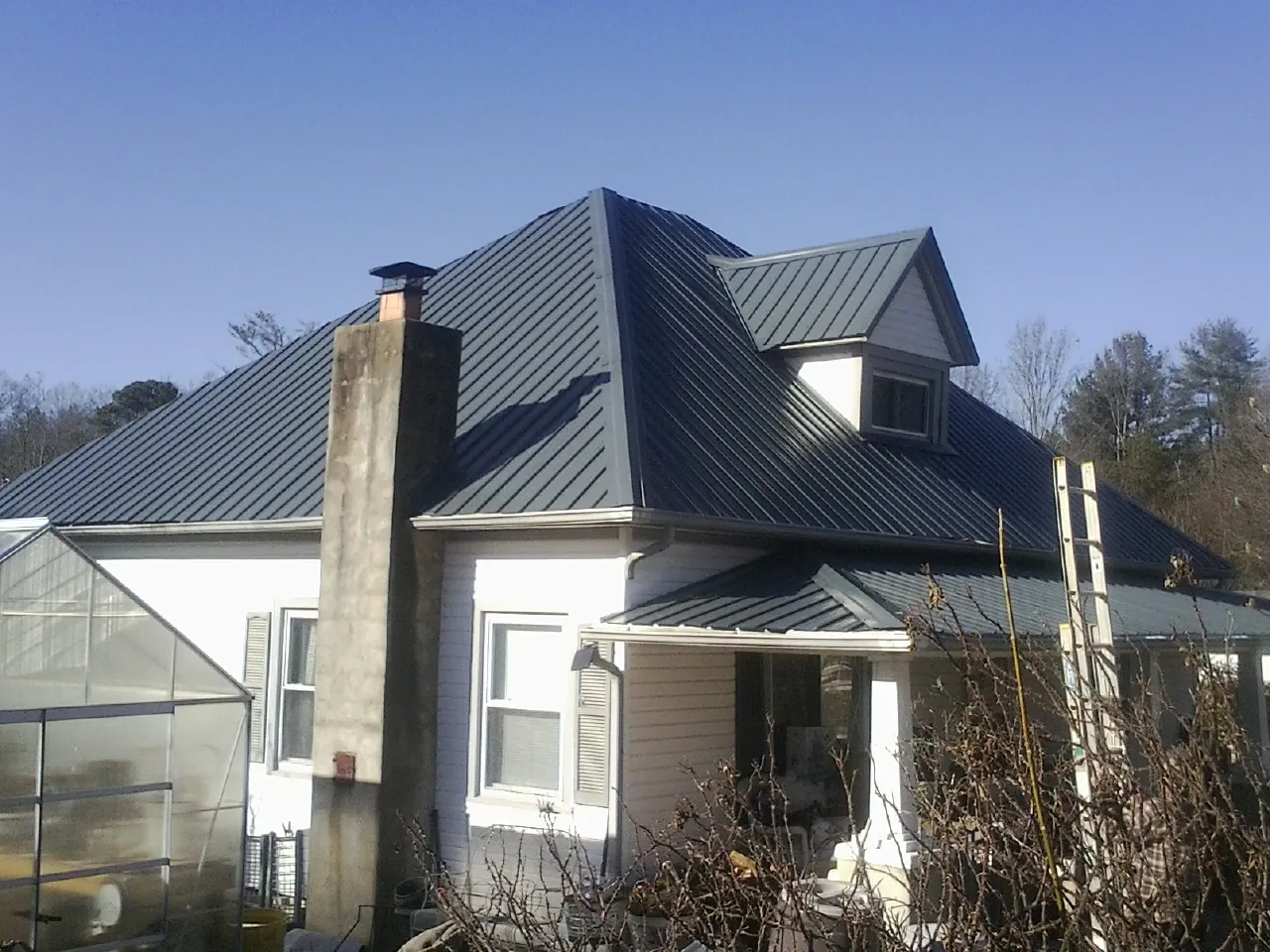 Dark blue standing seam metal roof on a white farmhouse with dormer — Slate & Tile Roof Repair by Roofing Brothers in Rowena