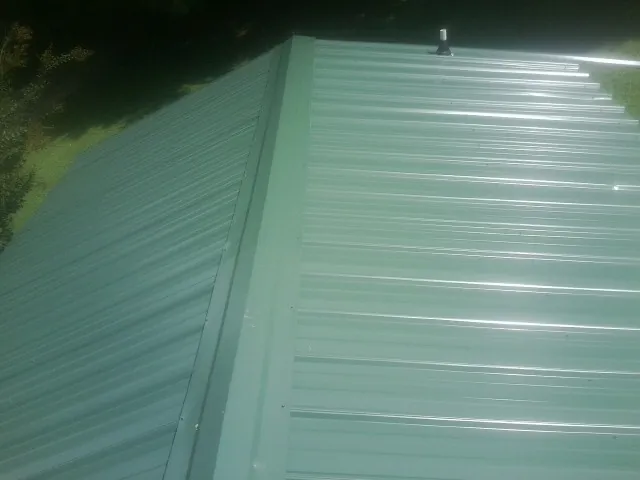 New green metal panels meeting at the ridge of a roof — Flat Roof Repair work by our crew in Rowena