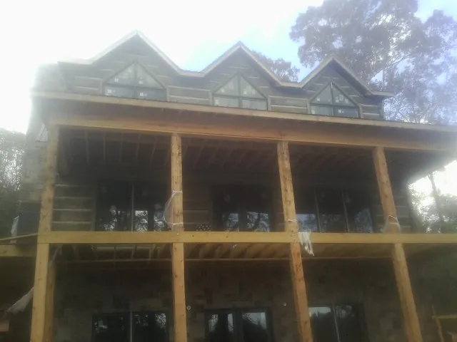 Dormers and porch framing on a large log home under construction — Roof Coating work by our crew in Rowena