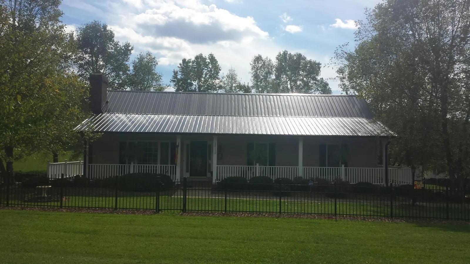 Gray metal roof on a brick ranch with a full width front porch — Gutter Guard Installation work by our crew in Rowena