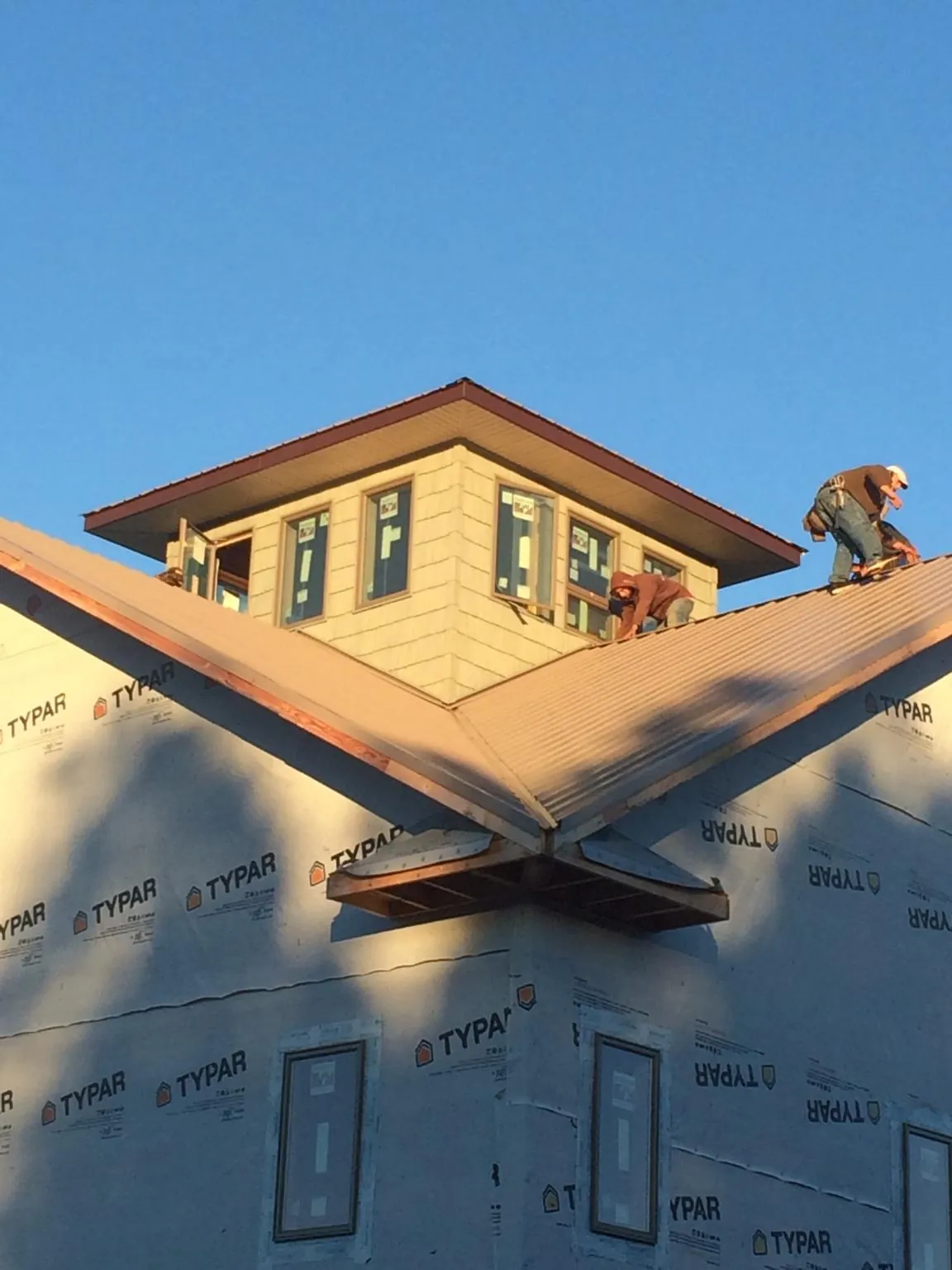 Roofers working around a rooftop cupola on a new metal roof at sunset — Roof Waterproofing in Rowena by Roofing Brothers